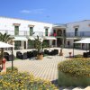Edificio bianco con cortile, sedie e tavolini all'aperto, circondato da fiori.