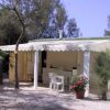 Una casa mobile con terrazza e sedie, immersa tra alberi e ghiaia.