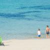 Due bambini sulla riva del mare, sedia e ombrellone sulla sabbia.