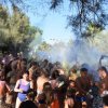 Festa con lancio di polveri colorate, persone festanti all'aperto tra gli alberi.