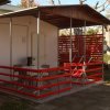 Bungalow bianco con veranda, tavolino e sedie rosse.
