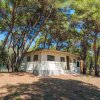 Una piccola casa tra gli alberi con tetto a spiovente e finestre con inferriate.