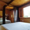 Camera da letto in legno con letto bianco, armadio e finestra aperta.