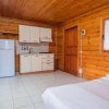 Cucina in legno con frigorifero, armadietti, fornello e letto singolo vicino a una finestra.