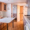 Cucina con tavolo, panca, piano cottura e lavello, porta verso altra stanza.