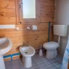 Bagno con pareti in legno, sanitari bianchi e doccia nascosta. Finestra con vetro opaco.