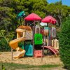 Parco giochi colorato con scivoli e tetti rossi immerso nella natura verde.