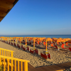 Spiaggia con ombrelloni e sedie a sdraio arancioni.