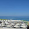 Spiaggia con ombrelloni bianchi e colorati, mare calmo e cielo sereno.