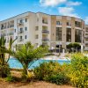Un edificio moderno a più piani accanto a una piscina con piante verdi in primo piano.