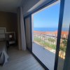 Camera con letto e grande finestra che si affaccia su un balcone con vista sul mare.