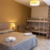 Una camera con letto matrimoniale, letti a castello, poltrona e lampada a soffitto.