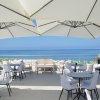 Una terrazza con sedie bianche e grandi ombrelloni bianchi vista mare.