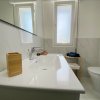 Un moderno bagno bianco con lavabo, finestra e decorazioni in legno.