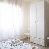 Camera con armadio bianco, tendaggi e letto con copriletto a motivi blu.