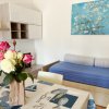 Tavolo con tovaglia stampata, vaso di fiori, divano blu e quadro floreale azzurro.