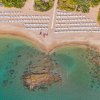 Vista aerea di una spiaggia con lettini e acqua cristallina.