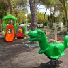 Area giochi con dinosauro a molla e scivolo.