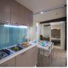 Cucina moderna con mobili beige, tavolo apparecchiato, finestra luminosa e pavimento in legno.