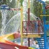 Bambini sotto spruzzi d'acqua e scivolo colorato.