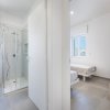 Bagno e camera con letti singoli, vista da un corridoio.