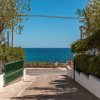Viale verso il mare con cancello verde aperto.