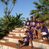 Gruppo di persone in magliette viola su gradini circondati da palme.