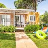 Una casa mobile con veranda e sedie a sdraio colorate in un giardino verde.