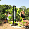 Due persone usano un attrezzo fitness all'aperto tra gli alberi.