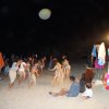 Festa sulla spiaggia di notte con persone che ballano.