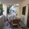 Una terrazza con tavolo e sedie in legno, circondata da piante.