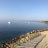 Spiaggia tranquilla con staccionata e barche in mare calmo.