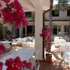 Spazio esterno di un ristorante con tavoli bianchi e bouganville rosa in primo piano.