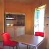 Interno moderno con due sedie rosse e tavolo quadrato. Porta aperta e piccolo angolo cottura.