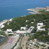 Costa con spiaggia, case tra alberi e mare; vista aerea.