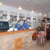 Interno di un bar con due persone dietro il bancone e una famiglia davanti.