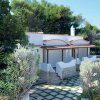Casa bianca circondata da vegetazione, con pietra e tetto in terracotta, vista esterna.