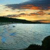 Spiaggia al tramonto con cielo rosso e mare mosso.