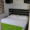 Camera da letto con letto matrimoniale, lenzuola bianche e coperta verde.