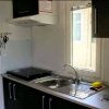 Cucina compatta con lavello, fornelli e utensili appesi.