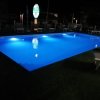 Piscina illuminata di notte con sedie a sdraio attorno.
