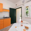 Cucina interna con mobili arancioni, tavolo apparecchiato e porta aperta su un balcone.