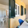 Patio con tavolo e sedie, vista su cucina interna, persiane verdi.