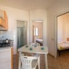 Cucina con tavolo e sedie, piano cottura, porte che conducono a camere da letto.