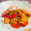 Un piatto di pasta con frutti di mare, pomodori e prezzemolo.