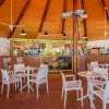 Locale con tavoli e sedie bianche, bar con insegna 