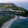 Vista aerea di una spiaggia, mare e vegetazione densa nelle vicinanze.