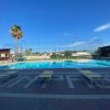 Piscina all'aperto con lettini, palme e cielo azzurro.