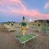 Ombrelloni verdi e gialli chiusi su una spiaggia al tramonto con cielo rosa.