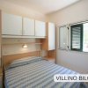 Una camera da letto con letto matrimoniale, mobili bianchi e una finestra aperta.